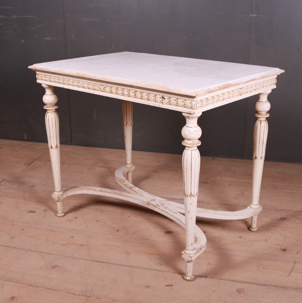 A Gustavian off-white painted lamp table featuring carved frieze detailing, gilt accents, fluted tapered legs, and a curved stretcher base. View IV