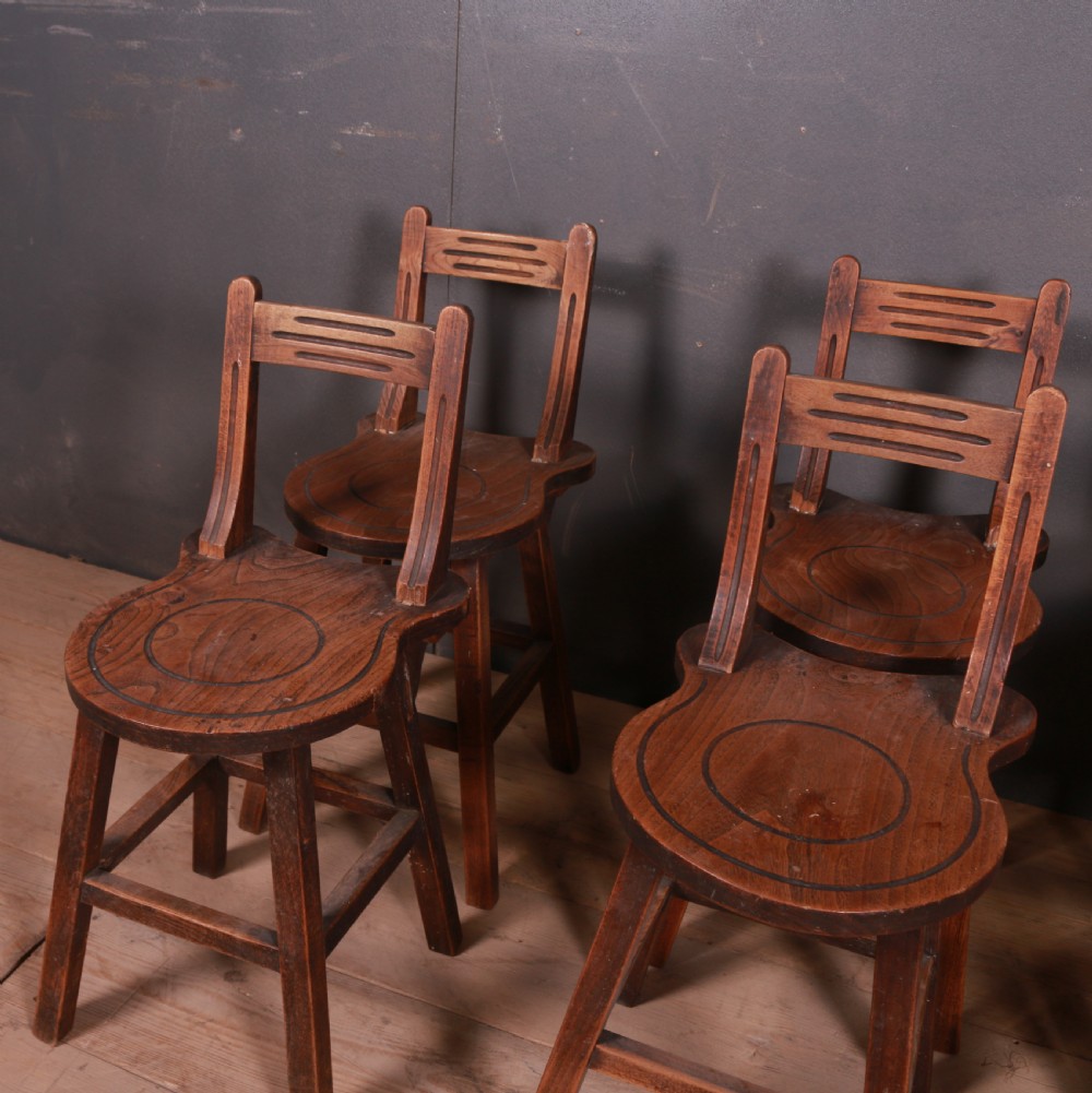 A set of six warm brown Swiss elm back stools featuring pierced top crest rails, circular carved seat details, and splayed legs with stretchers. View III