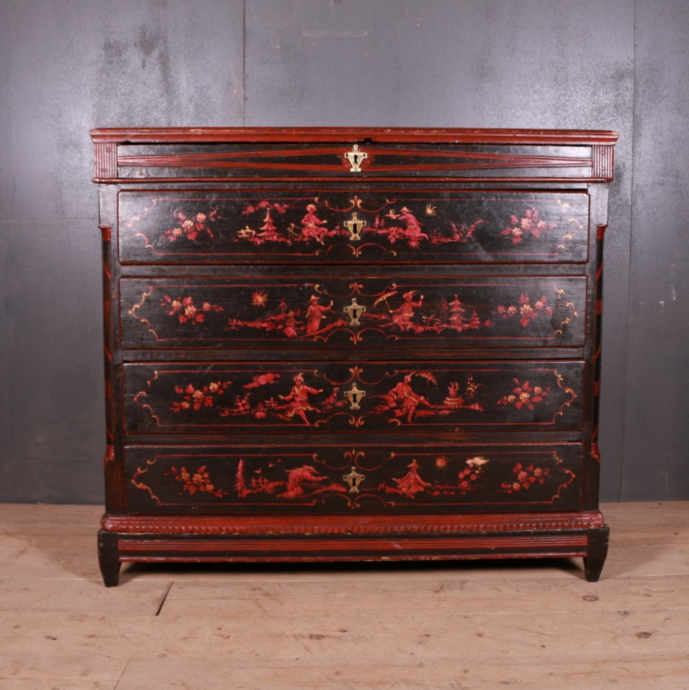 A Northern European lacquered chest of drawers featuring red and gold chinoiserie landscape scenes painted on a black background with brass escutcheons.