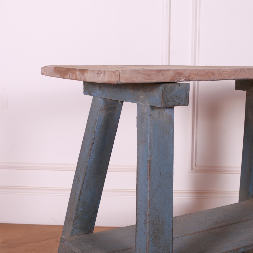 A rustic pine trestle table featuring a natural unpainted wood top and distressed blue painted A-frame legs with a lower storage shelf. View III