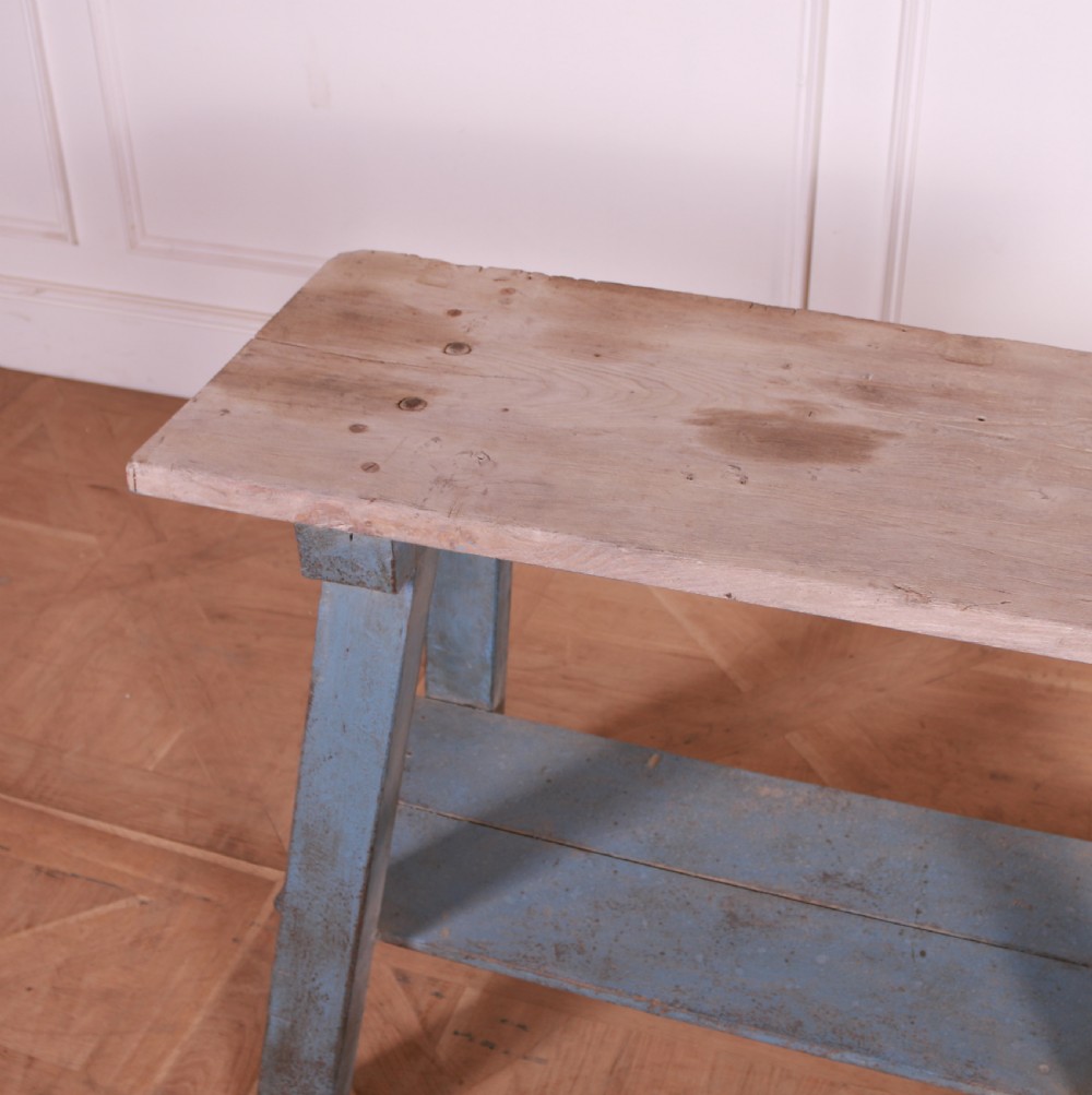 A rustic pine trestle table featuring a natural unpainted wood top and distressed blue painted A-frame legs with a lower storage shelf. View V