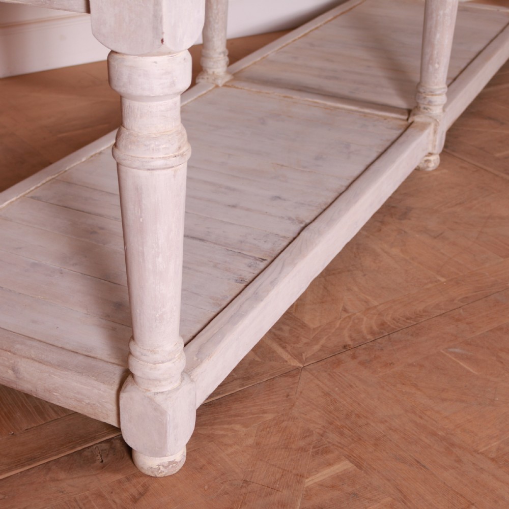 A long French painted drapers table featuring a natural wood top, six turned legs, a distressed white paint finish, and a full-length lower shelf. View IV