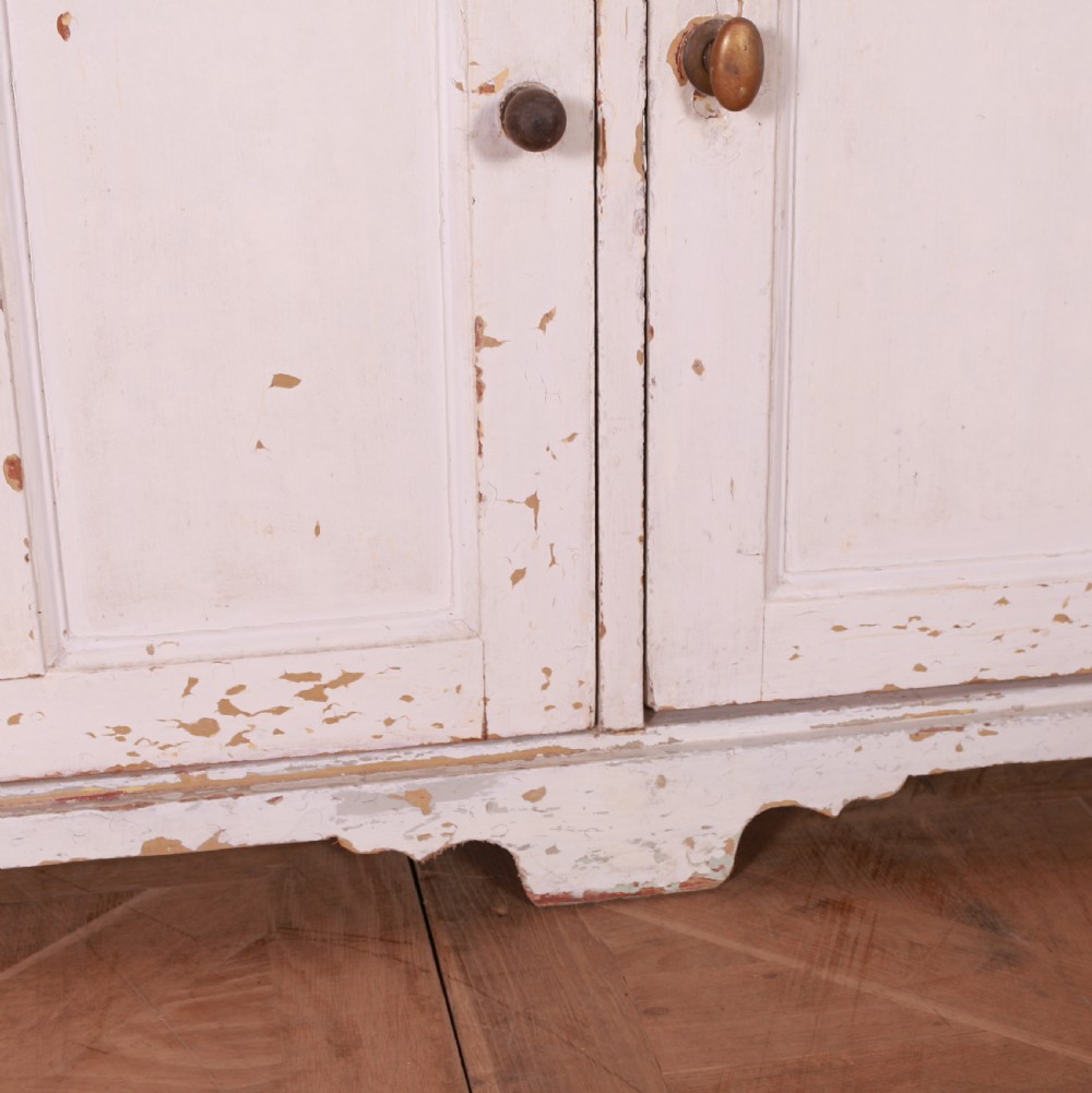 A Scottish painted pine dresser base with three top drawers over three panelled cupboard doors, featuring a natural timber top with a low gallery back and a distressed off-white painted finish. View VI
