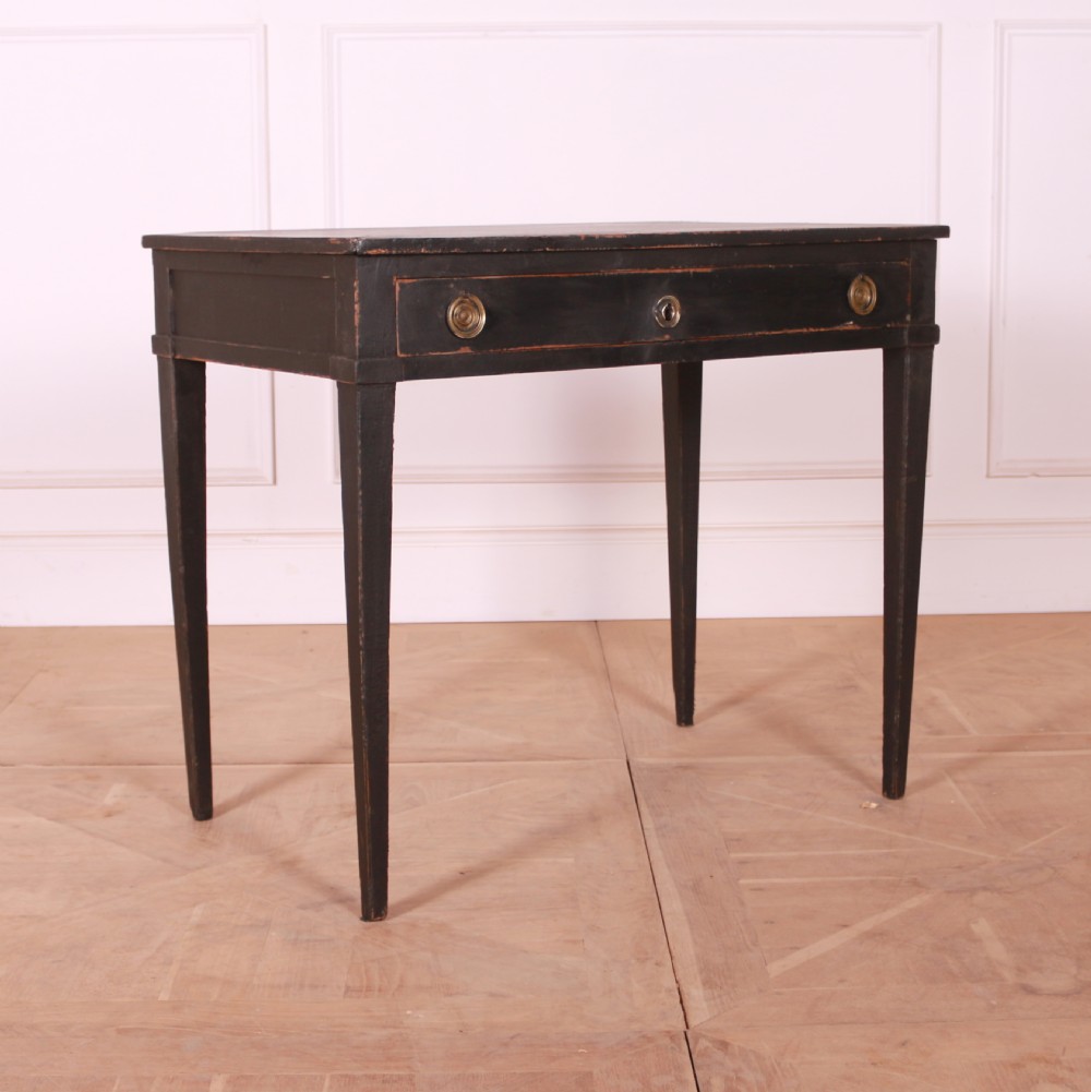 A rectangular black painted French side table featuring a single frieze drawer, brass handles, and square tapered legs.