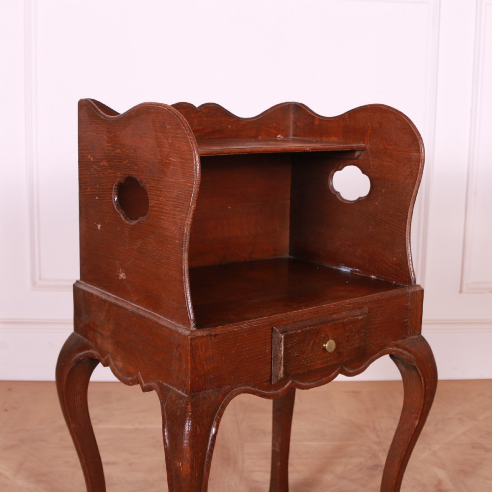 A French oak bedside table with slender cabriole legs, a single drawer, and a tray-top gallery featuring cut-out side handles. View II