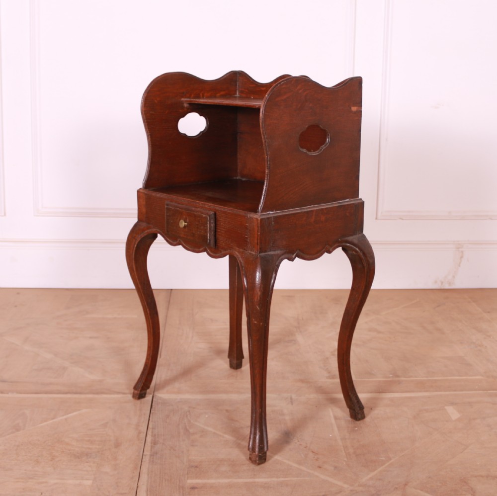 A French oak bedside table with slender cabriole legs, a single drawer, and a tray-top gallery featuring cut-out side handles. View IV