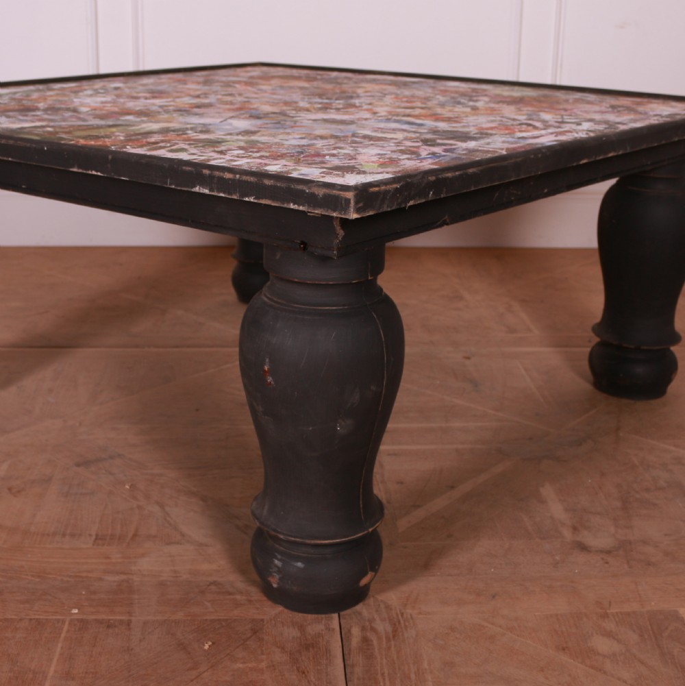 A large low square coffee table featuring heavy turned black legs and a colourful collage pattern inset into the tabletop surface. View II