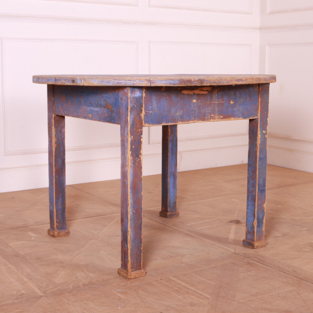 A round French provincial wooden dining table featuring a distressed blue painted finish over an exposed undercoat, supported by four square legs. View II
