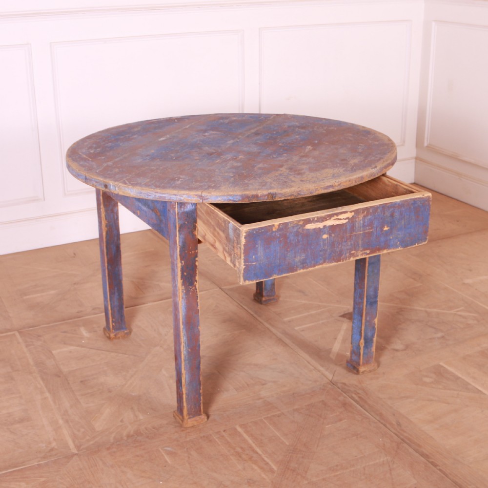 A round French provincial wooden dining table featuring a distressed blue painted finish over an exposed undercoat, supported by four square legs. View III