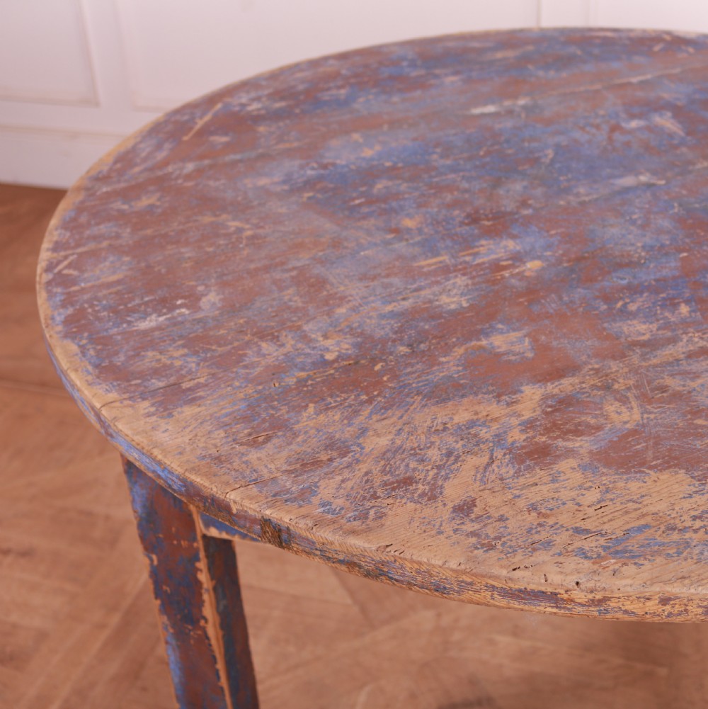A round French provincial wooden dining table featuring a distressed blue painted finish over an exposed undercoat, supported by four square legs. View IV