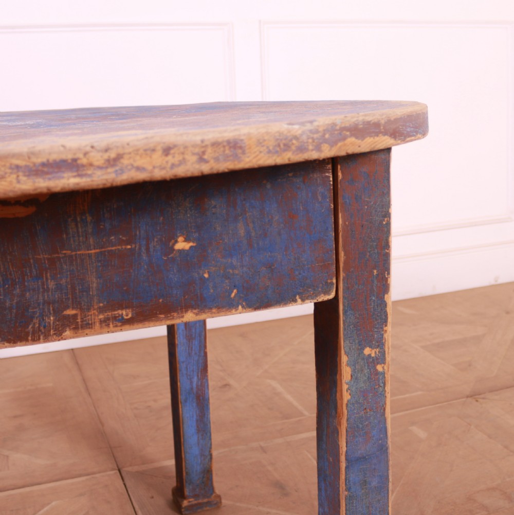 A round French provincial wooden dining table featuring a distressed blue painted finish over an exposed undercoat, supported by four square legs. View VI