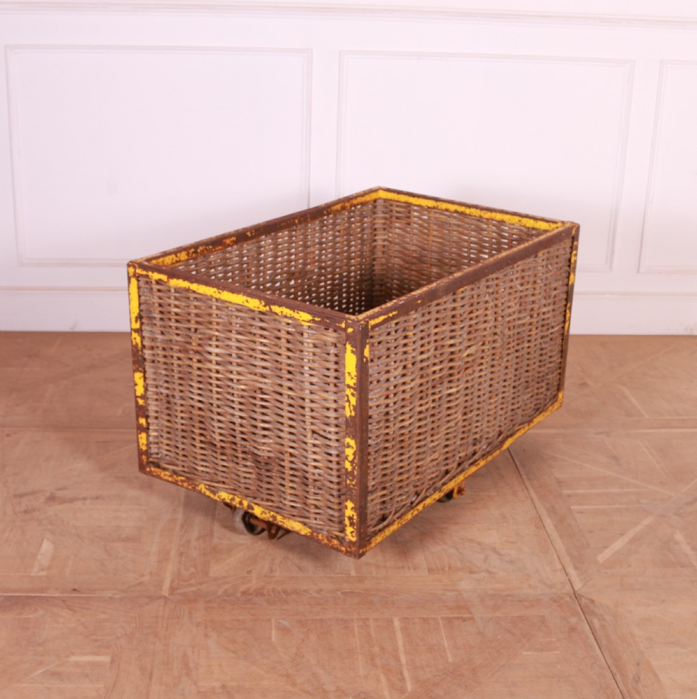 A large rectangular woven wicker basket enclosed in a distressed yellow painted steel frame with small castors on the base. View III