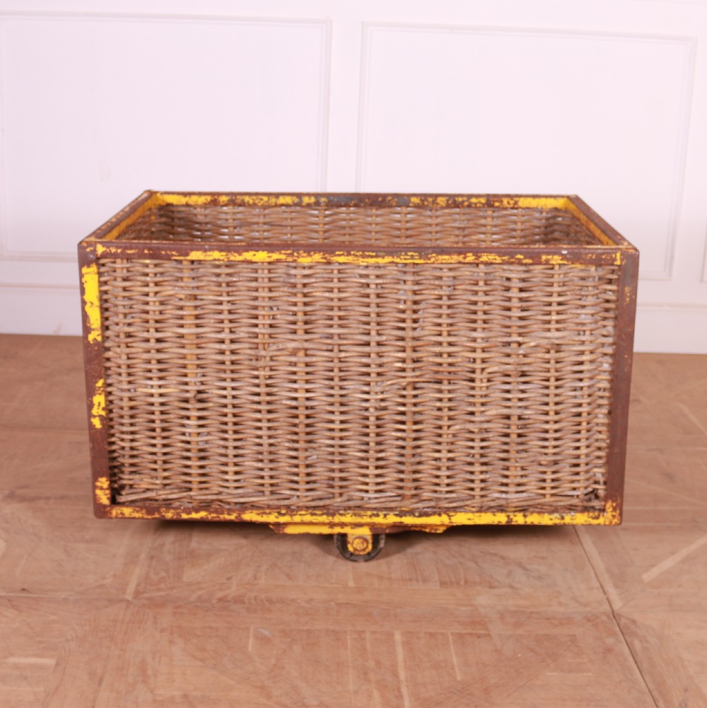 A large rectangular woven wicker basket enclosed in a distressed yellow painted steel frame with small castors on the base. View IV