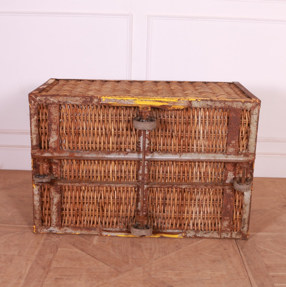 A large rectangular woven wicker basket enclosed in a distressed yellow painted steel frame with small castors on the base. View V