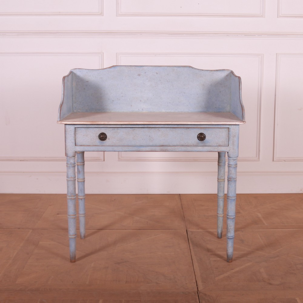 A pale blue painted side table featuring a raised gallery back, single drawer with two circular metal knobs, and ring-turned legs.