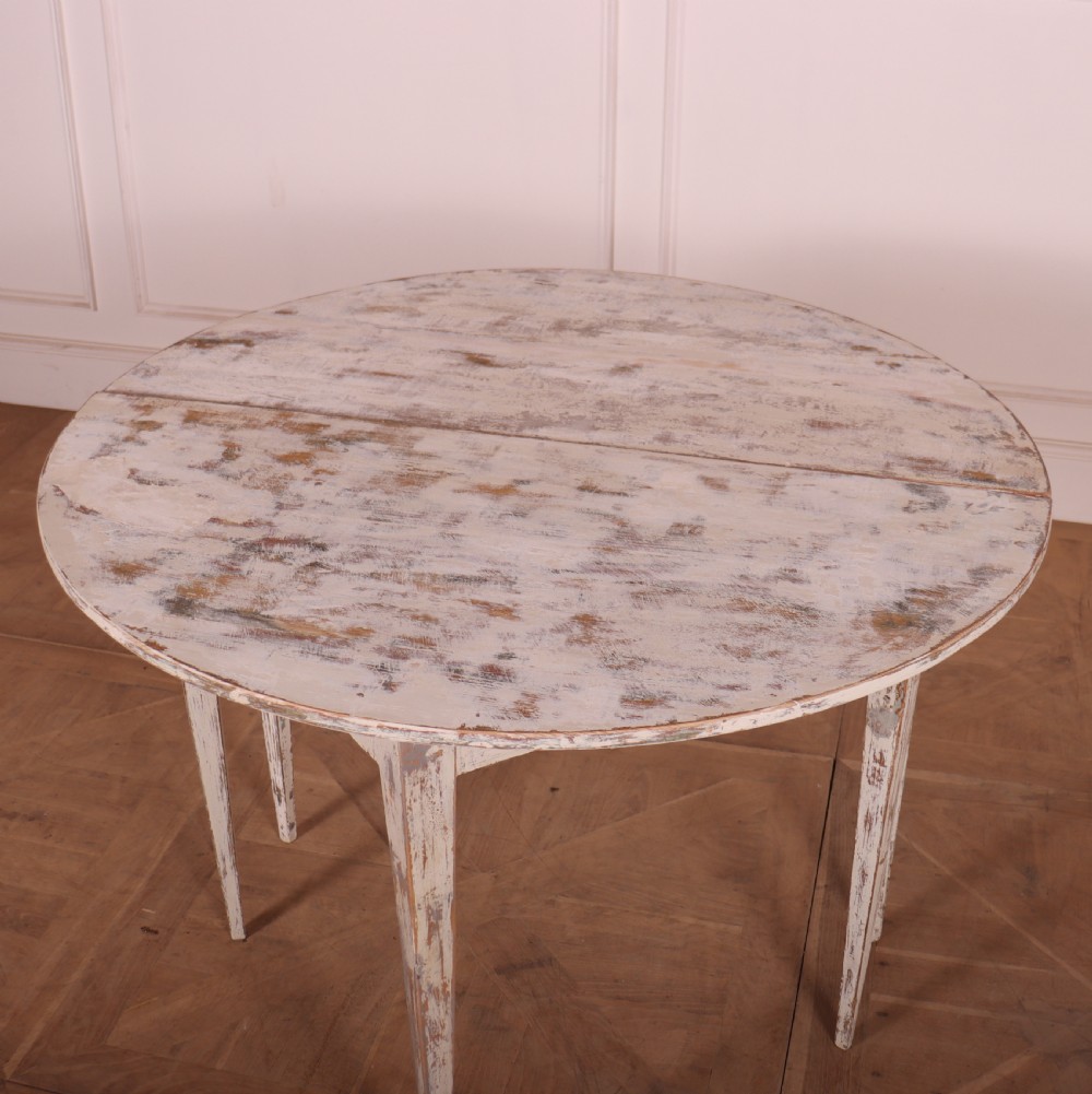 A pair of antique Swedish demi-lune console tables featuring distressed off-white painted finishes and simple tapered legs. View VI