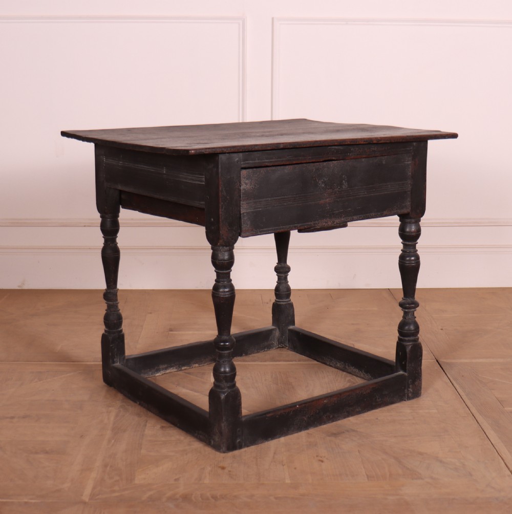 An 18th-century dark painted wooden side table with a single drawer, turned legs, and low box stretchers.
