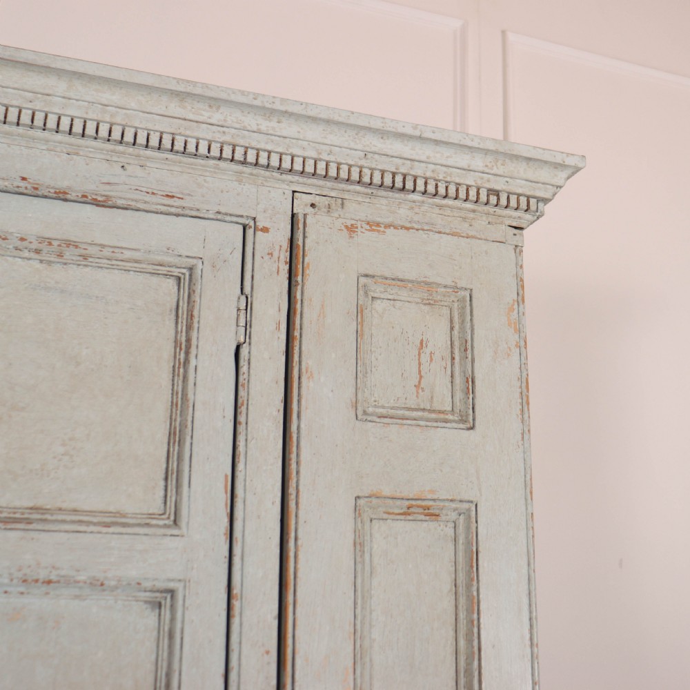 A small antique English housekeepers cupboard with a pale blue painted finish, panelled doors, turned wooden knobs, and bracket feet. View V