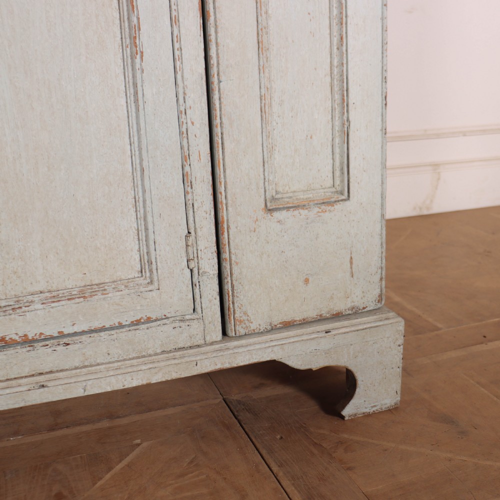 A small antique English housekeepers cupboard with a pale blue painted finish, panelled doors, turned wooden knobs, and bracket feet. View VI