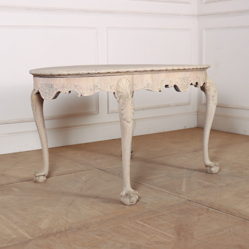 An antique bleached oak centre table with a carved apron, cabriole legs, and shell motifs resting on a parquet floor. View II