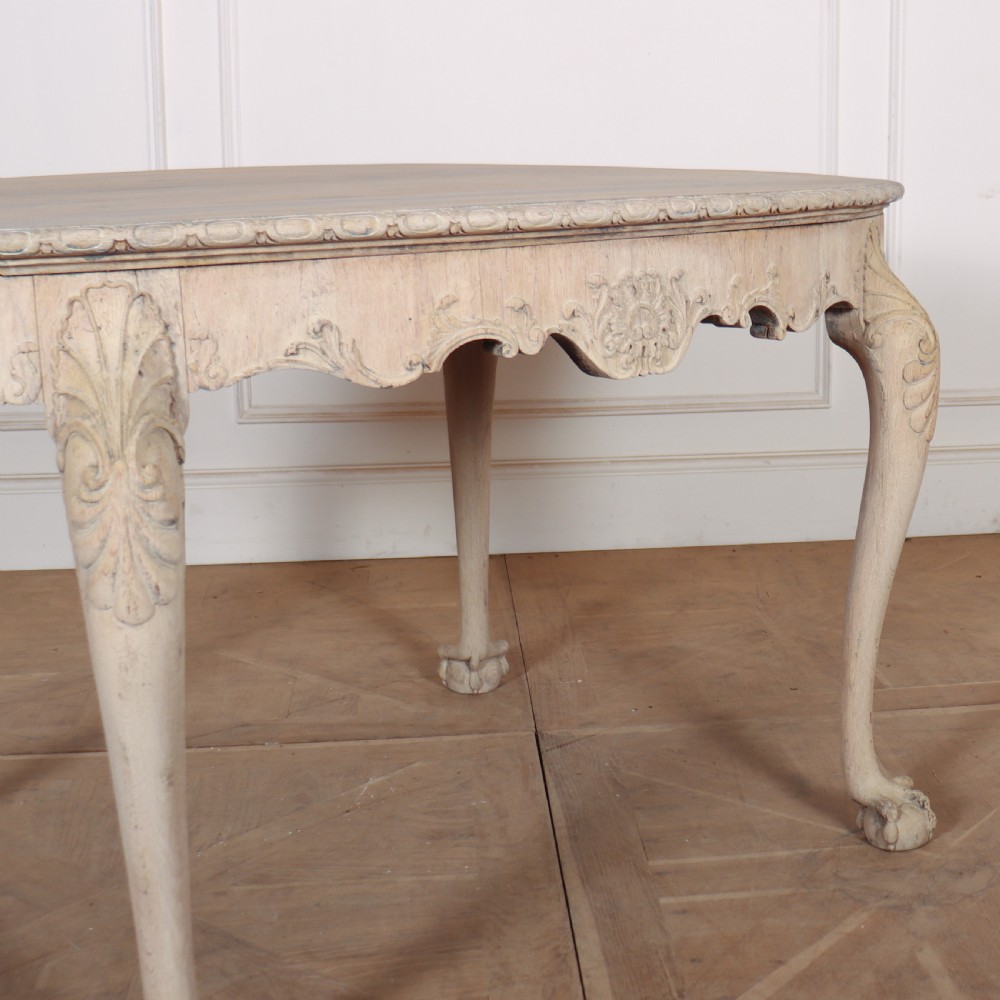 An antique bleached oak centre table with a carved apron, cabriole legs, and shell motifs resting on a parquet floor. View IV