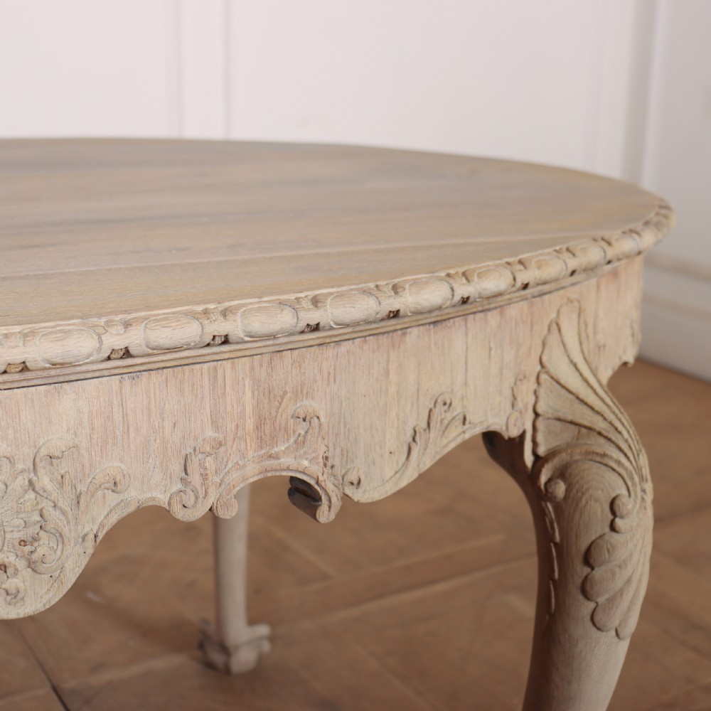 An antique bleached oak centre table with a carved apron, cabriole legs, and shell motifs resting on a parquet floor. View VI