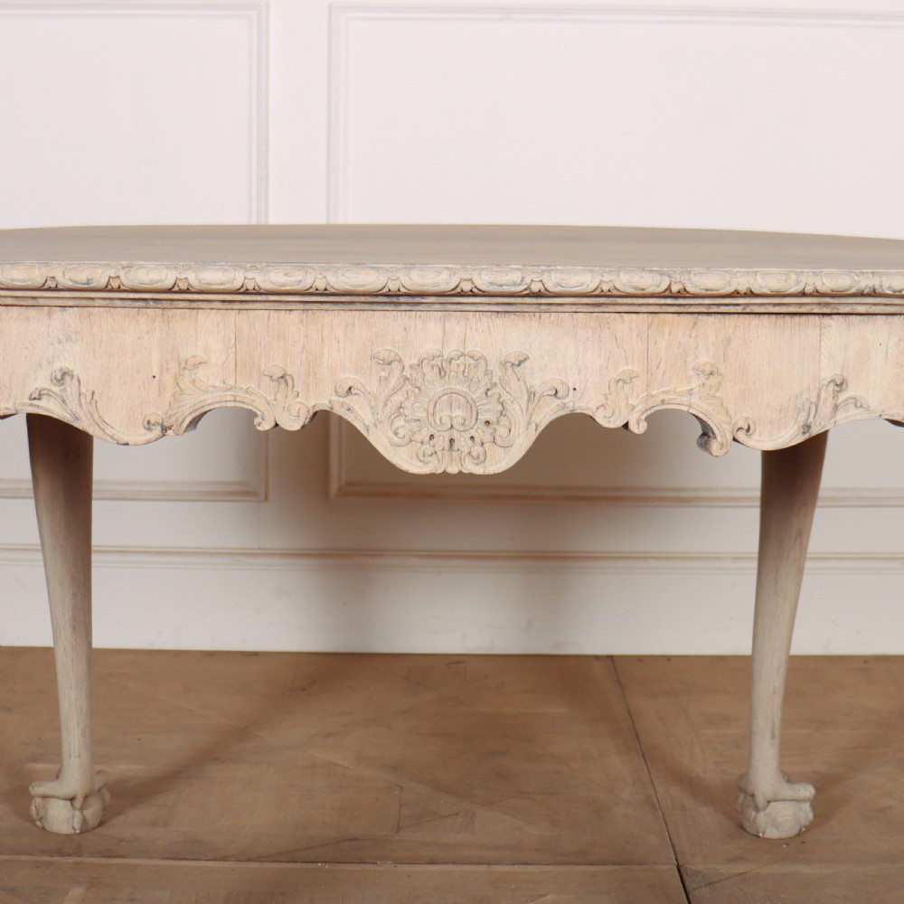 An antique bleached oak centre table with a carved apron, cabriole legs, and shell motifs resting on a parquet floor. View VII