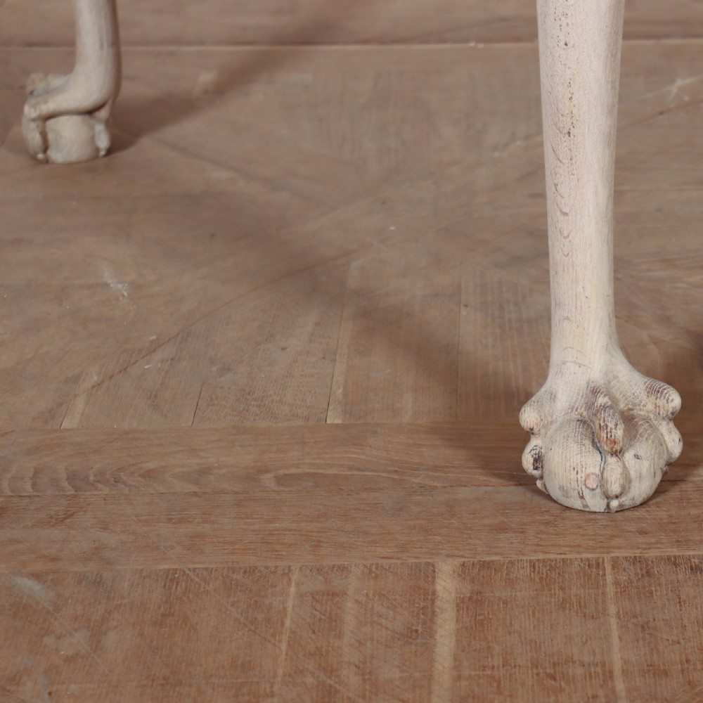 An antique bleached oak centre table with a carved apron, cabriole legs, and shell motifs resting on a parquet floor. View VIII
