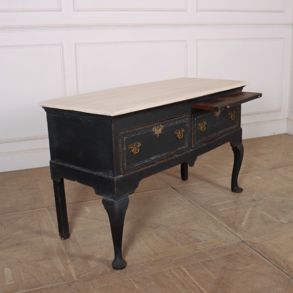 An 18th-century black painted wooden dresser base featuring two drawers with ornate brass handles, a light top, shaped apron, and four cabriole legs. View IV