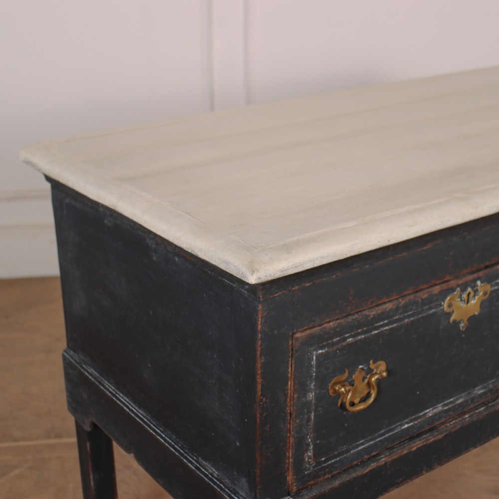 An 18th-century black painted wooden dresser base featuring two drawers with ornate brass handles, a light top, shaped apron, and four cabriole legs. View V
