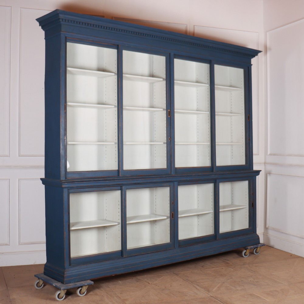 A large two-tier blue painted display cabinet featuring sliding glass doors and a white painted interior fitted with shelves.