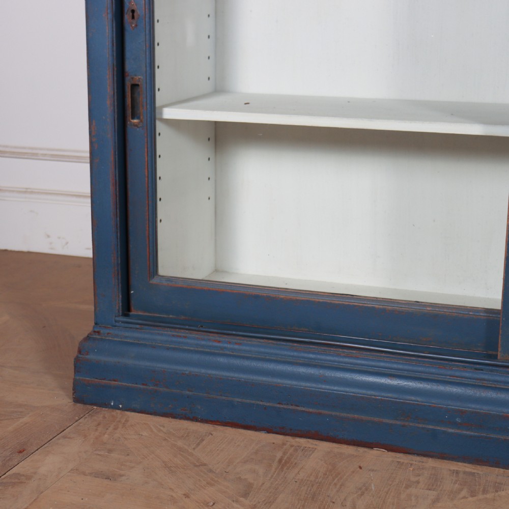 A large two-tier blue painted display cabinet featuring sliding glass doors and a white painted interior fitted with shelves. View III