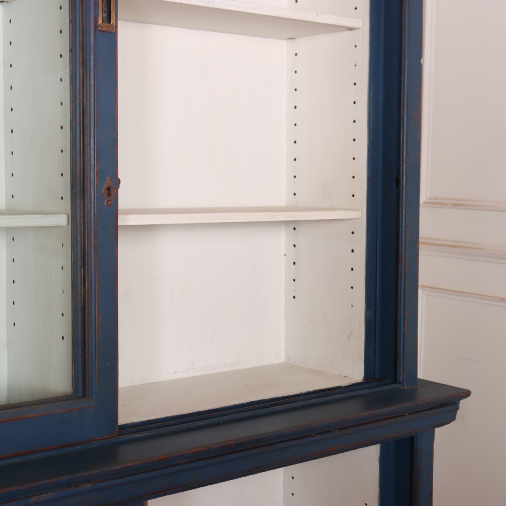 A large two-tier blue painted display cabinet featuring sliding glass doors and a white painted interior fitted with shelves. View V