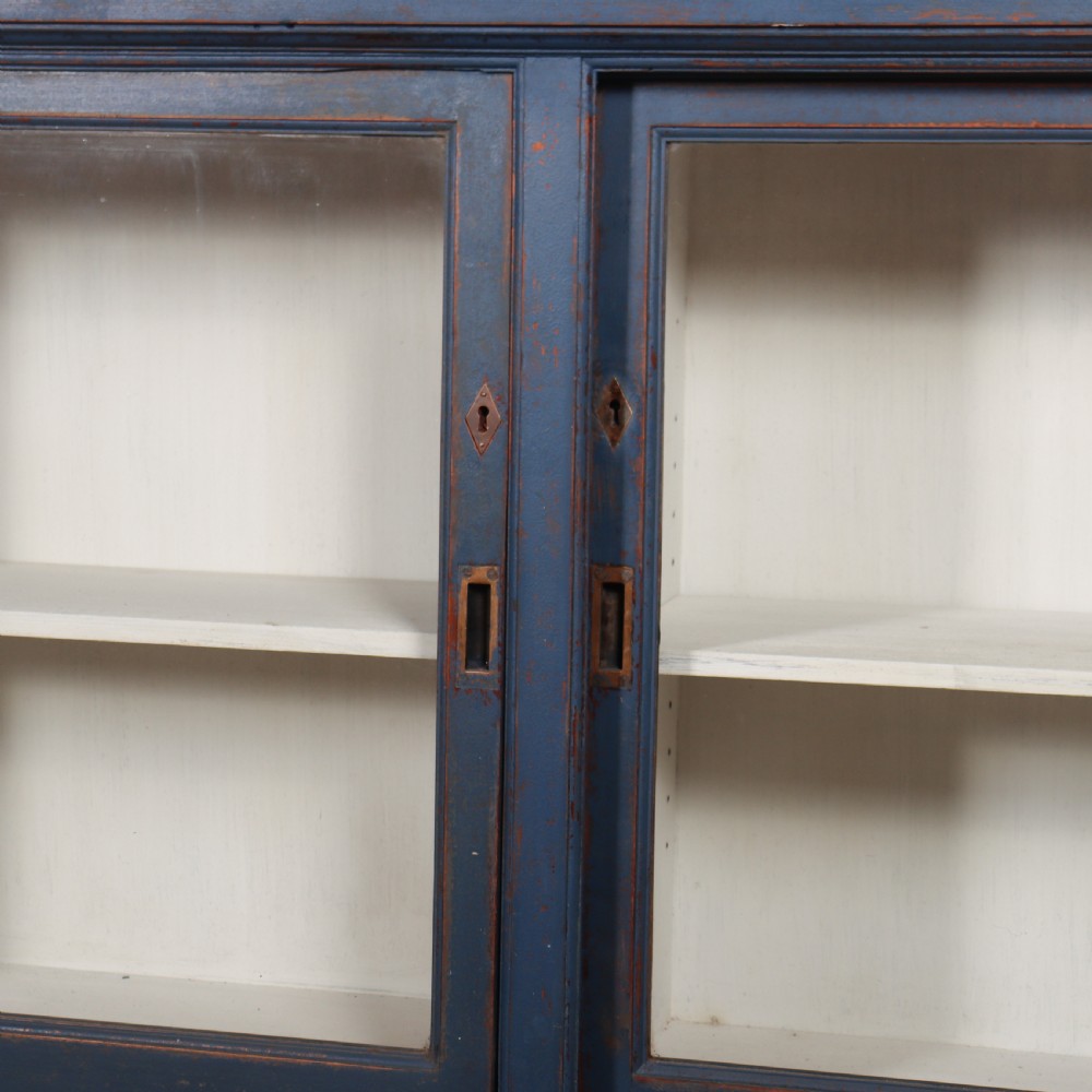 A large two-tier blue painted display cabinet featuring sliding glass doors and a white painted interior fitted with shelves. View VI