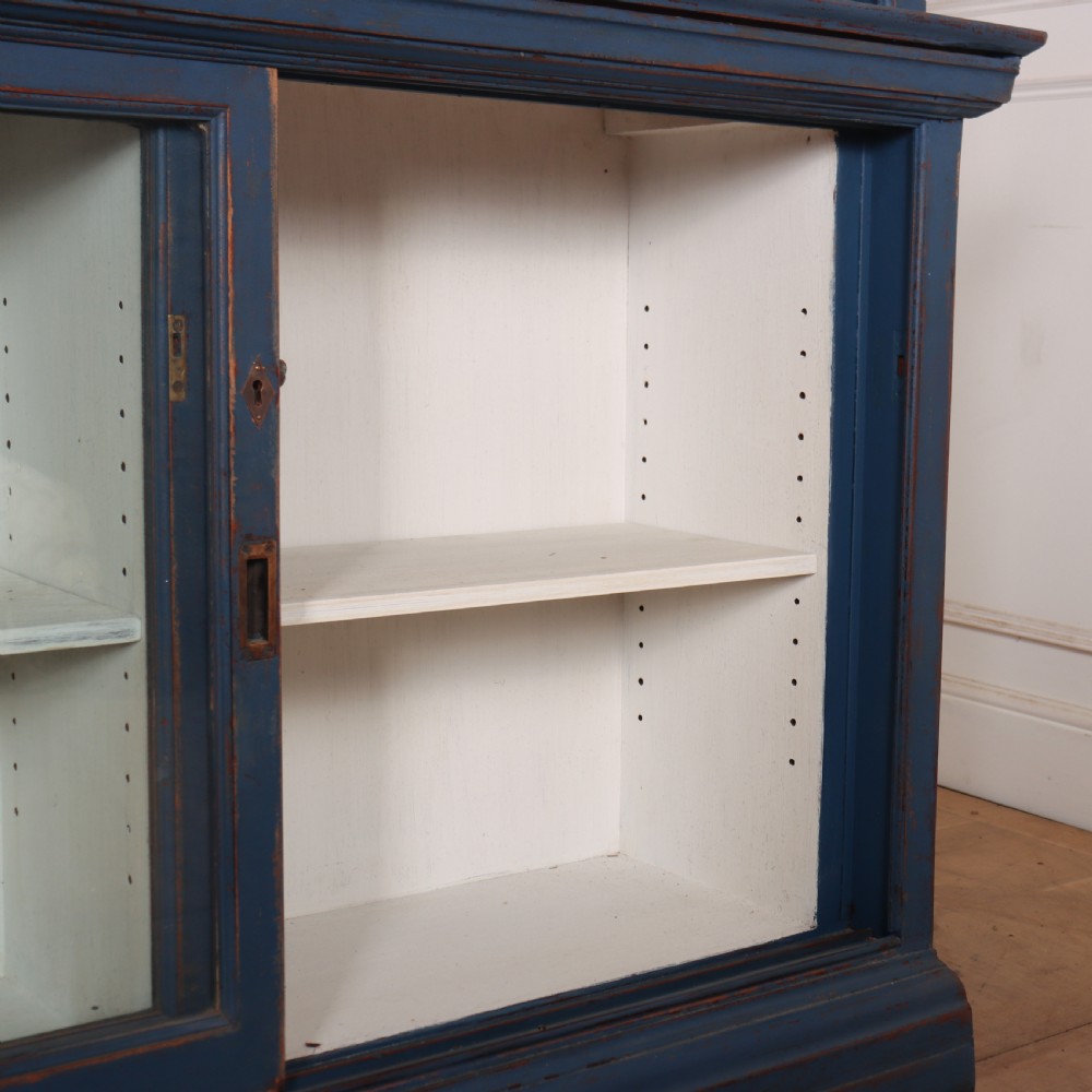 A large two-tier blue painted display cabinet featuring sliding glass doors and a white painted interior fitted with shelves. View VII