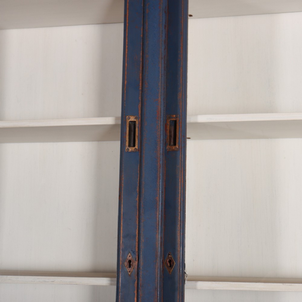 A large two-tier blue painted display cabinet featuring sliding glass doors and a white painted interior fitted with shelves. View X