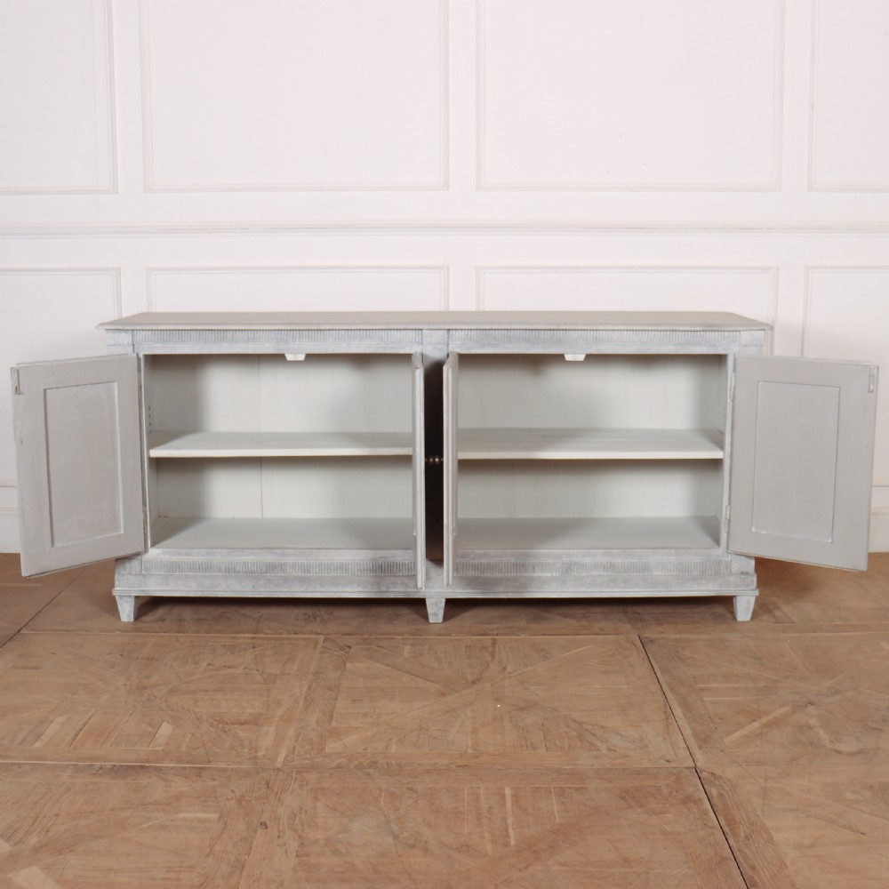 A pair of Swedish enfilades featuring a distressed pale grey painted finish, panelled cupboard doors, small round brass knobs, and short tapered legs. View IV
