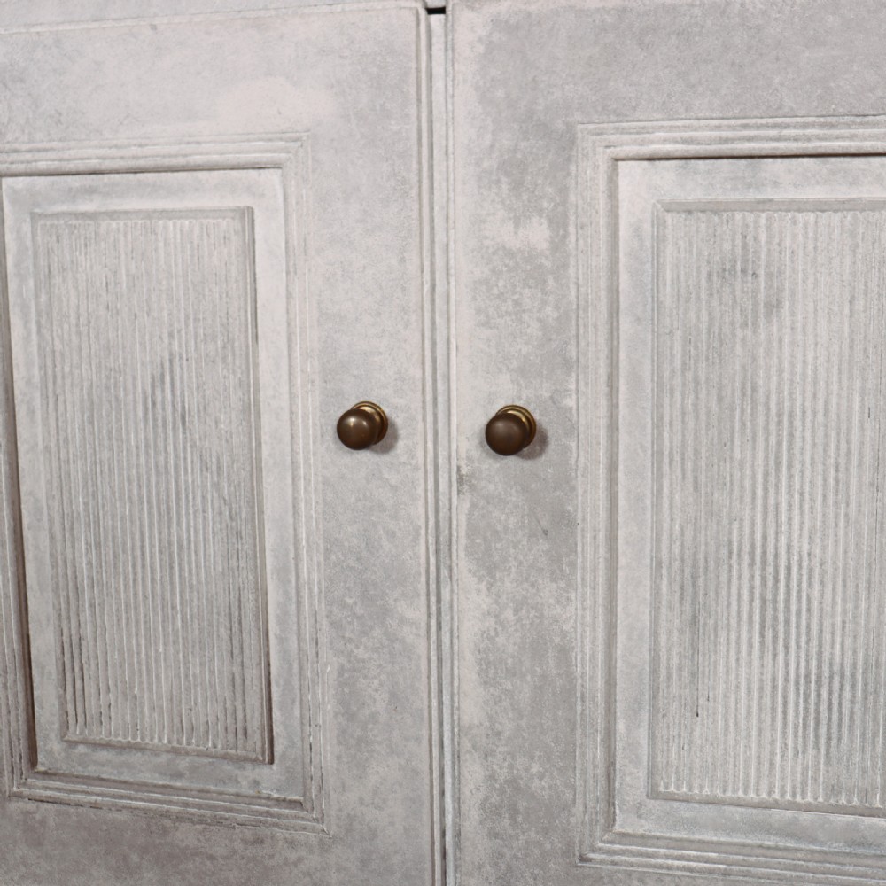 A pair of Swedish enfilades featuring a distressed pale grey painted finish, panelled cupboard doors, small round brass knobs, and short tapered legs. View VIII