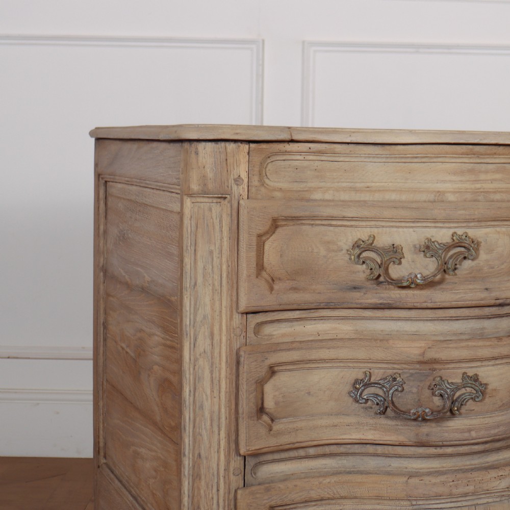 An 18th-century bleached oak French commode with three moulded serpentine drawers featuring brass handles and key escutcheons. View II