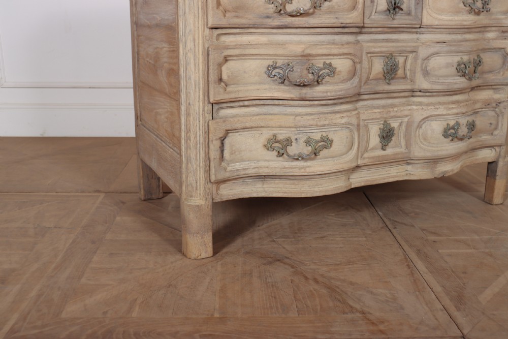 An 18th-century bleached oak French commode with three moulded serpentine drawers featuring brass handles and key escutcheons. View III