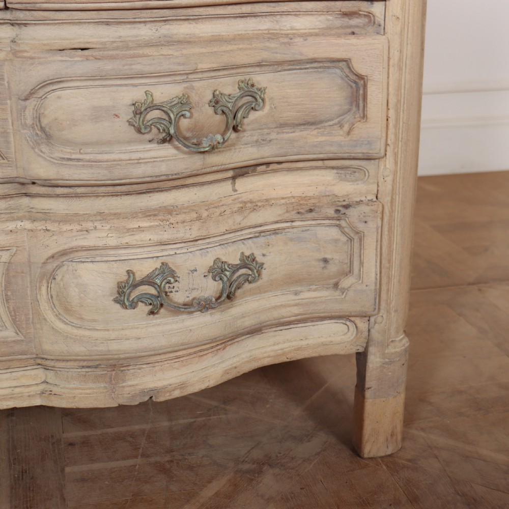 An 18th-century bleached oak French commode with three moulded serpentine drawers featuring brass handles and key escutcheons. View VII