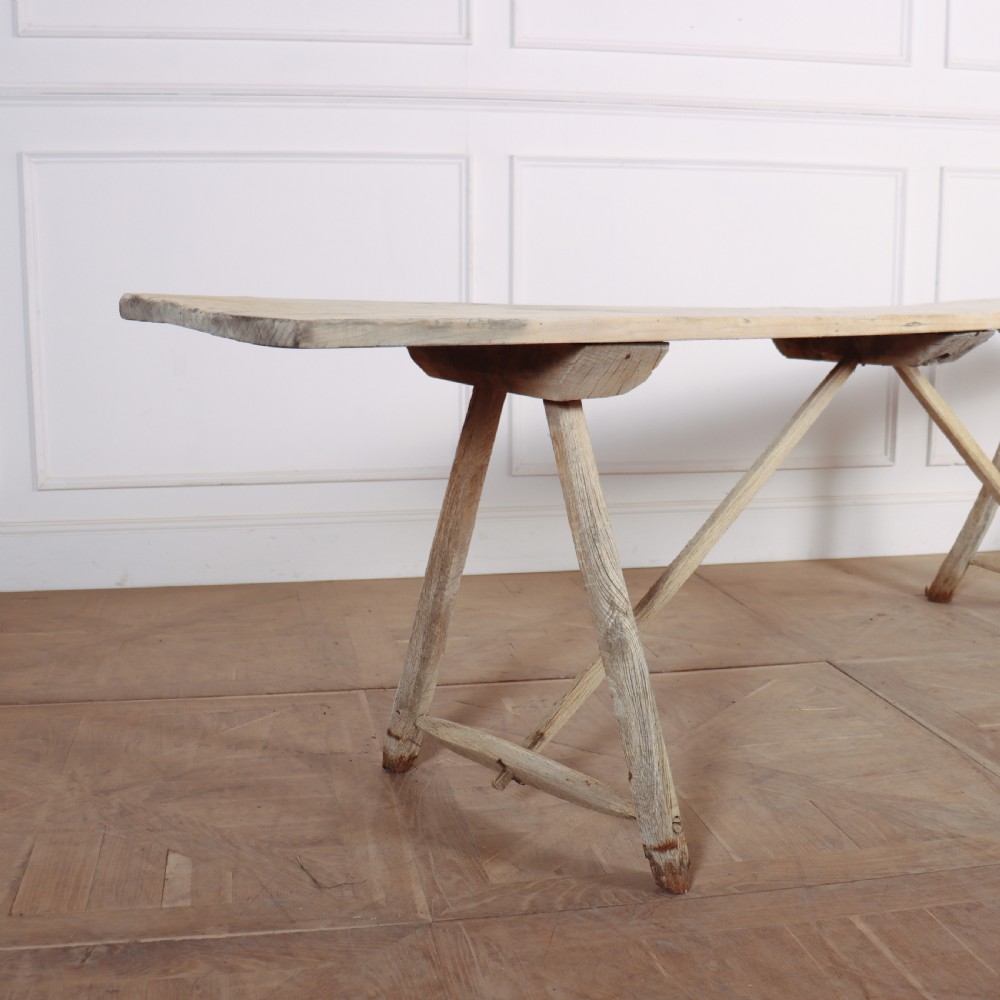 A long, narrow French rustic trestle table constructed from pale oak and poplar timber with A-frame leg supports. View II