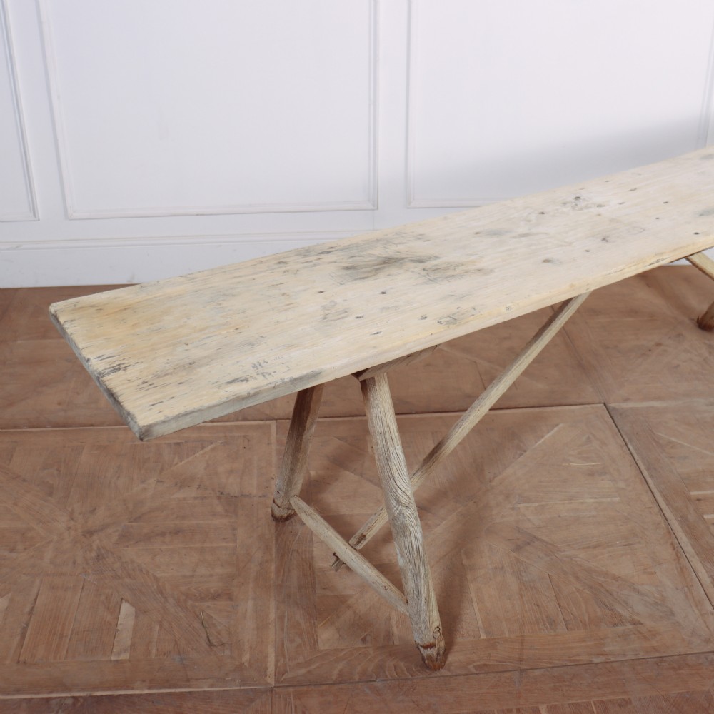 A long, narrow French rustic trestle table constructed from pale oak and poplar timber with A-frame leg supports. View IV