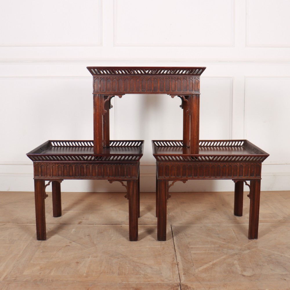 A set of three dark mahogany lamp tables featuring pierced gallery rims and Gothic arch fretwork aprons.