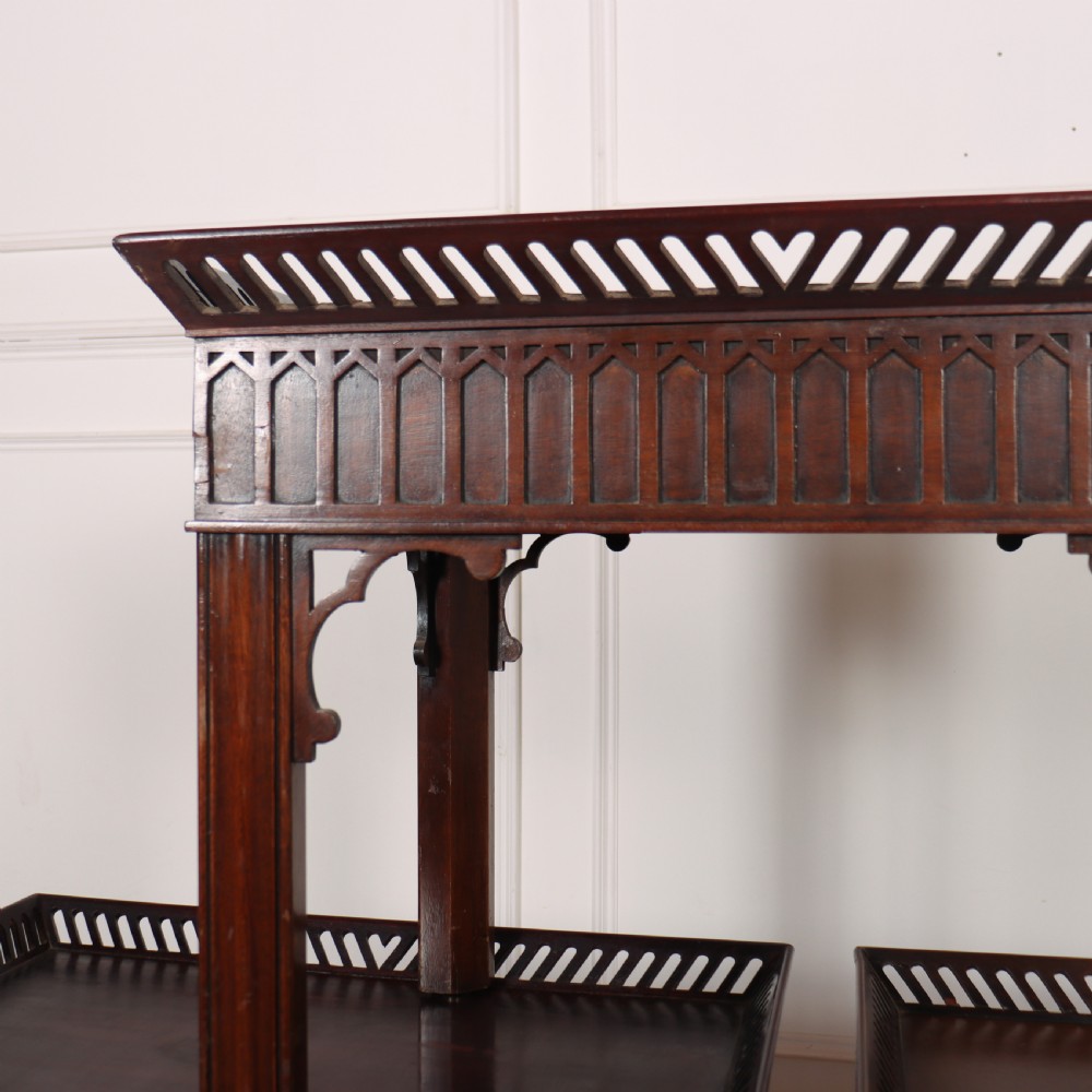 A set of three dark mahogany lamp tables featuring pierced gallery rims and Gothic arch fretwork aprons. View V