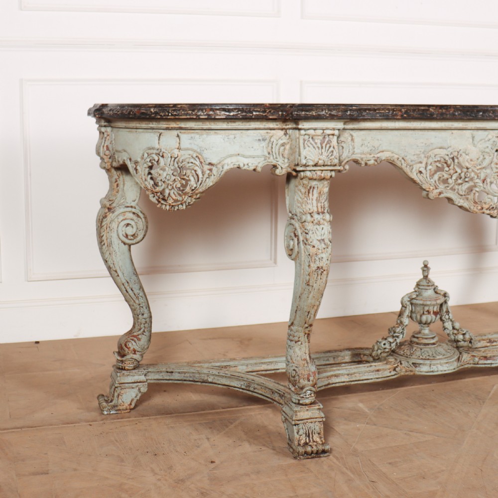 A carved Spanish console table featuring distressed pale blue paintwork, a dark rectangular top, an intricate carved apron, and a central urn finial stretcher. View II
