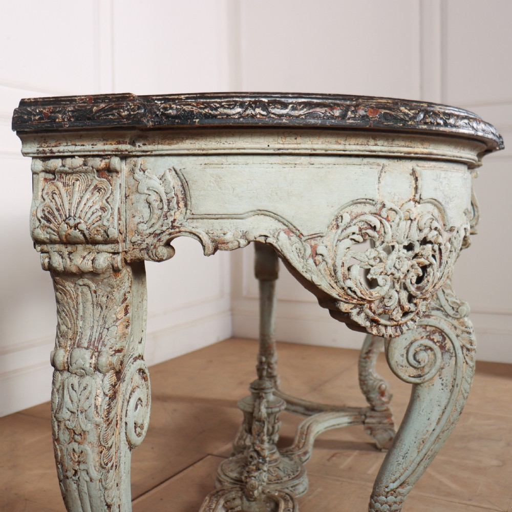 A carved Spanish console table featuring distressed pale blue paintwork, a dark rectangular top, an intricate carved apron, and a central urn finial stretcher. View V