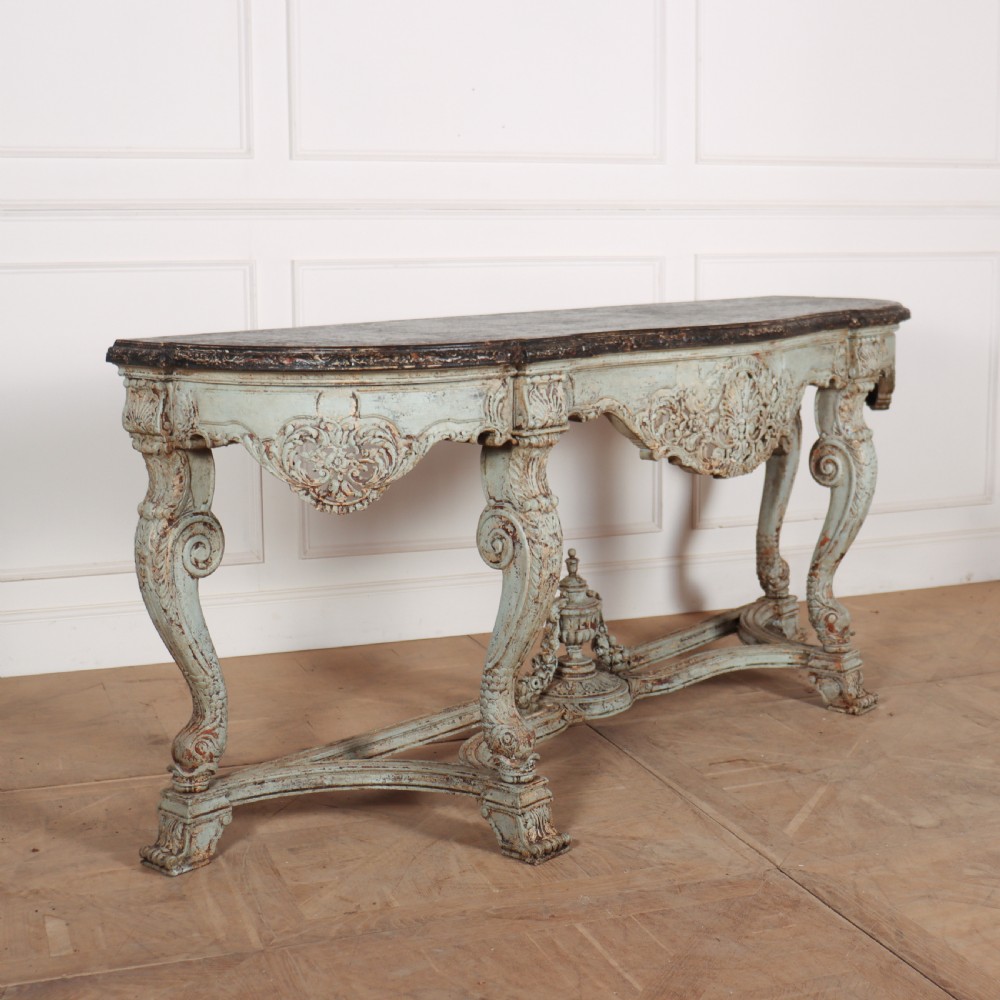 A carved Spanish console table featuring distressed pale blue paintwork, a dark rectangular top, an intricate carved apron, and a central urn finial stretcher. View VI