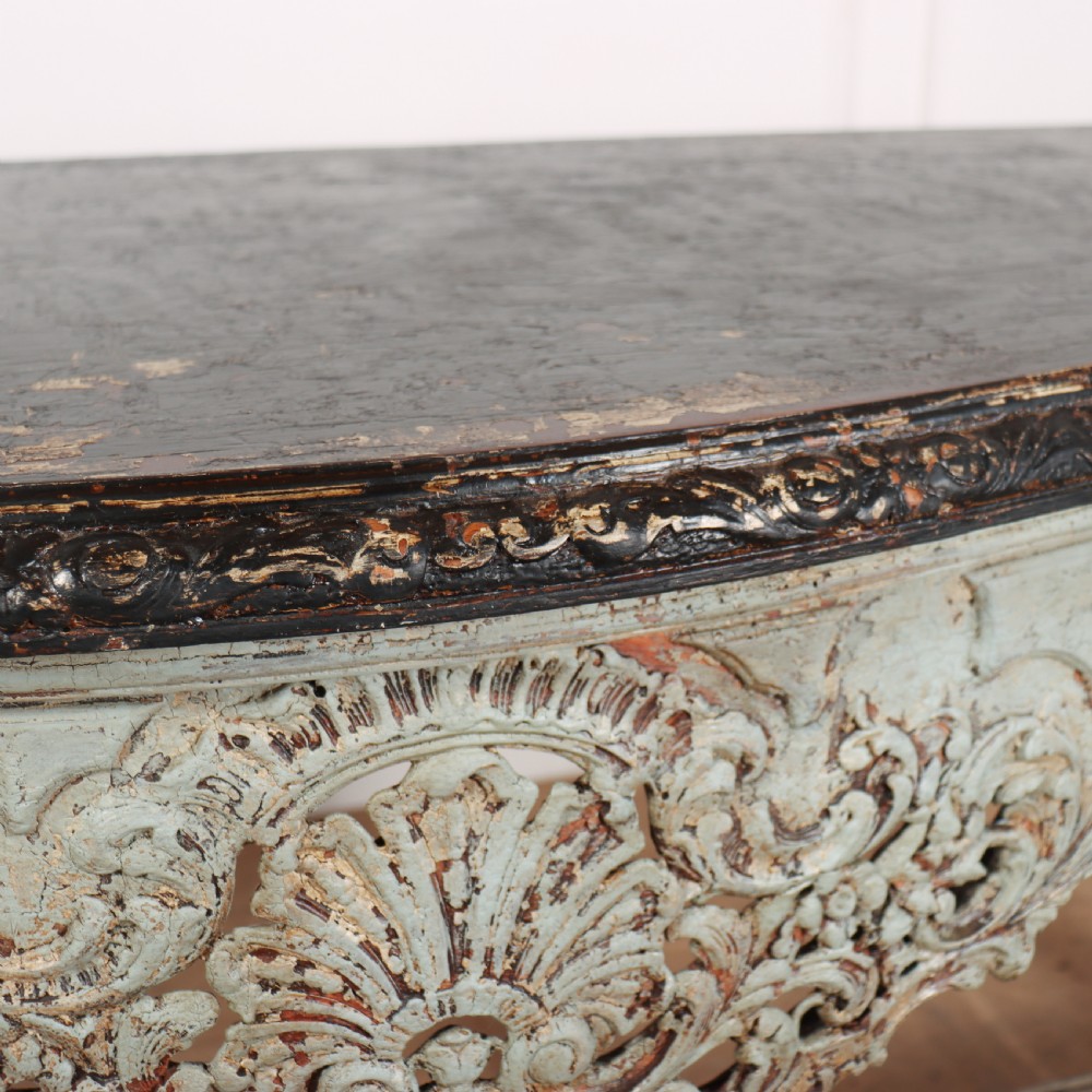 A carved Spanish console table featuring distressed pale blue paintwork, a dark rectangular top, an intricate carved apron, and a central urn finial stretcher. View XI