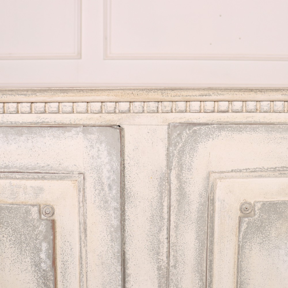 An 18th-century Swedish painted wooden linen cupboard featuring panelled double doors, brass keyhole escutcheons, and a distressed off-white painted finish. View IV